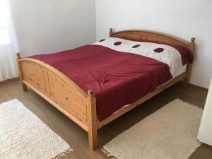 a wooden bed with a red and white comforter at Kovács apartman in Balatonberény