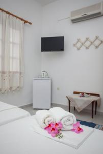 a hotel room with two towels and flowers on a bed at Anestoula Rooms in Skala