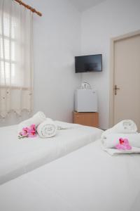 a bedroom with a white bed with towels and a tv at Anestoula Rooms in Skala