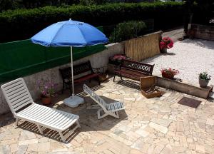 a patio with two chairs and a blue umbrella at Patty green house in Castellana Grotte
