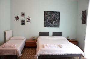 two beds in a room with white sheets at Patty green house in Castellana Grotte