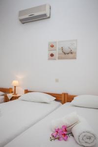 two beds with white sheets and pink flowers on them at Anestoula Rooms in Skala