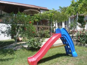 a red and blue playground slide in a yard at Green Leaves in Iraklitsa