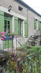 una casa con puertas verdes y flores delante de ella en Gite de charme au coeur de la Bourgogne, en Santigny