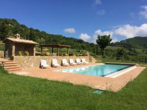 a swimming pool with chairs and a stone wall at Agriturismo Paradiso 44 in Assisi