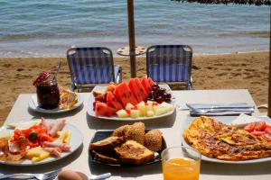 a table with plates of food on the beach at Edem Luxury Apartments in N&eacute;a P&eacute;ramos