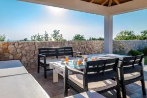 a patio with tables and chairs and a stone wall at Villa Daly in Primošten
