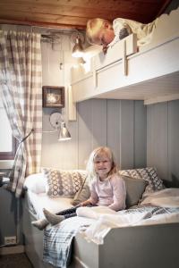 a little girl sitting on a bed in a room at Lifjellstua in Lifjell