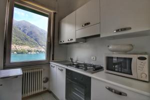 a kitchen with a stove and a microwave and a window at Hotel Bersagliere in Laglio