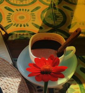 une tasse de café et une fleur rouge sur une assiette dans l'établissement Guerrera Rice Paddy Villas, à Mambajao