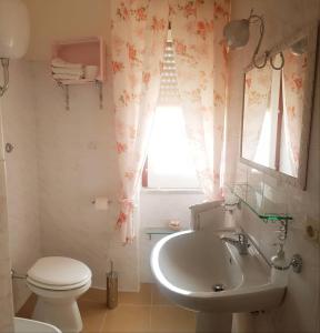 baño con lavabo y aseo y ventana en B&B Kalinìkta, en Ascea