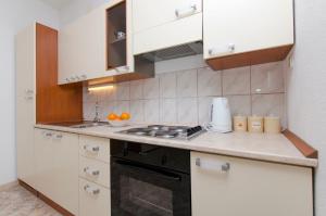 a kitchen with white cabinets and a stove top oven at Apartment Rosa in Primošten