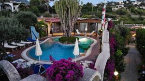 eine Aussicht über einen Pool mit Sonnenschirmen und Blumen in der Unterkunft Residence Giardino del Sole in Ischia