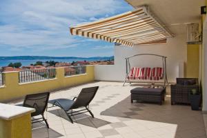 a patio with chairs and a swing on a balcony at Apartment Noel in Kaštela