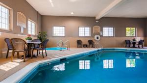 einen Pool mit einem Tisch und Stühlen neben einem Tisch und einem Tisch in der Unterkunft Best Western Plus North Joliet in Joliet