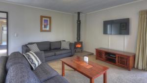 ein Wohnzimmer mit einem Sofa, einem Tisch und einem TV in der Unterkunft Bucks Point - Norfolk Island Holiday Homes in Burnt Pine