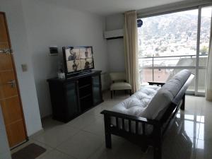 ein Wohnzimmer mit einem Sofa, einem TV und einem Fenster in der Unterkunft Departamento Edificio Manhattan 7mo piso in Villa Carlos Paz