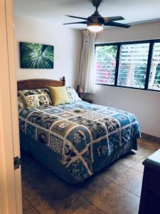 1 dormitorio con 1 cama y ventilador de techo en Aloha WAI en Kihei