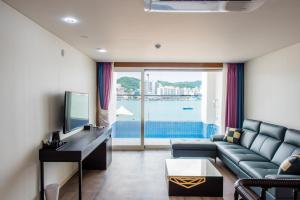 a living room with a couch and a tv at Fortuna Hotel in Tongyeong