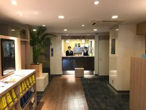 a lobby with two people standing at a counter in a store at Smile Hotel Tokyo Asagaya in Tokyo