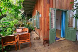 a wooden porch with chairs and an open door at Six Six Garden in Da Lat