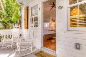 une maison blanche avec 2 chaises sur la terrasse couverte à l'avant dans l'établissement Key West Harbor Inn - Adults Only, à Key West