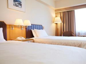 a hotel room with two beds and a window at Hotel New Otani Takaoka in Takaoka