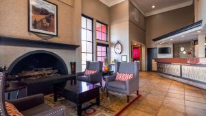 a living room with a fireplace and a table and chairs at Best Western Desert Villa Inn in Barstow