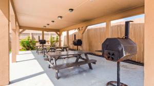 Carrizo SpringsBest Western Plus Carrizo Springs Inn & Suites的庭院里设有一排野餐桌和烧烤架 更多5张照片