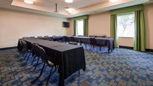 Carrizo SpringsBest Western Plus Carrizo Springs Inn & Suites的配有桌椅和屏幕的会议室