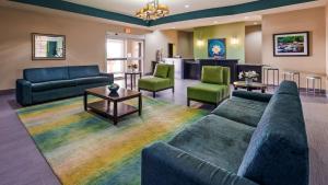 Carrizo SpringsBest Western Plus Carrizo Springs Inn & Suites的客厅配有沙发和椅子,位于彩虹地毯上