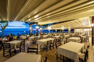 a restaurant with tables and chairs with a view of the ocean at Possidi Holidays Resort & Suite Hotel in Possidi