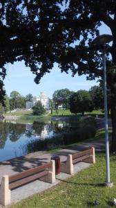 a park bench next to a lake with a building at Butas Vilniaus alėjoje in Druskininkai