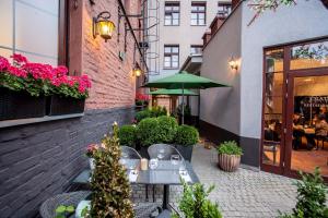 um pátio exterior com mesas e um guarda-chuva verde em Solaris em Toruń