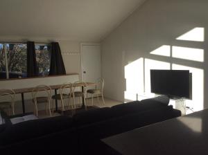 sala de estar con TV, mesa y sillas en Alpha Centauri Townhouses en Jindabyne