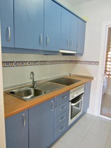 een keuken met blauwe kasten en een wastafel bij Riviera Golf apartment in Mijas Costa