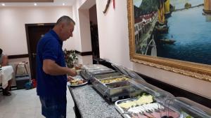 un hombre preparando un plato de comida en un buffet en Hotel Albania, en Velipojë