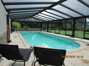 a swimming pool with a pergola and two chairs at Mon Doux Repos in Cambrai