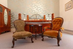 dwa krzesła i pianino w pokoju w obiekcie Villa Shakespeare w mieście Cambridge