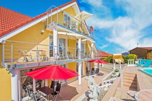 un gran edificio amarillo con sombrillas rojas y una piscina en Villa Europa en Heringsdorf