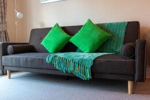 a couch with green pillows on it in a living room at Villa Shakespeare in Cambridge