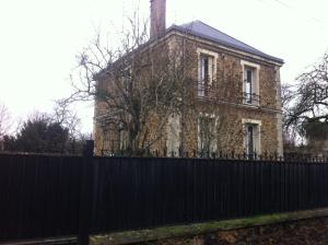 ein altes Backsteinhaus hinter einem schwarzen Zaun in der Unterkunft maison en pierre de taille in Le Raincy