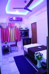 a bedroom with a bed and a table with flowers in it at Hotel Garuda Guntur in Guntūr