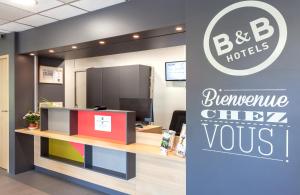 un panneau indiquant un bureau hypothécaire b b avec un comptoir de réception dans l'établissement B&B HOTEL CHAMBERY La Cassine, à Chambéry