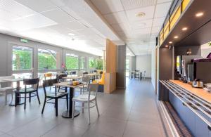 un coin repas avec des tables et des chaises dans un restaurant dans l'établissement B&B HOTEL CHAMBERY La Cassine, à Chambéry