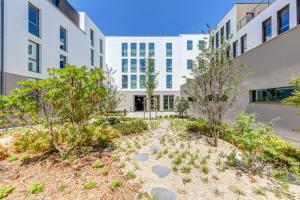 a courtyard with trees in front of a building at B&B HOTEL Paris Sud Chatenay Malabry in Châtenay-Malabry