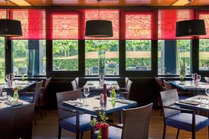 un restaurante con mesas, sillas y ventanas en Mercure Hotel Zwolle, en Zwolle