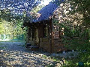 a small log cabin with a porch and a roof at Dom WIKTOR Kaszuby do 5 os. in Olpuch