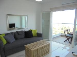 ein Wohnzimmer mit einem grauen Sofa und einem Tisch in der Unterkunft Kermia Court - Beach-front, modern 2 bedroom -sleeps 6 in Limassol