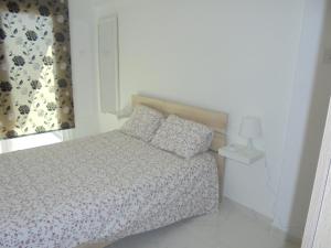 a white bedroom with a bed and a window at Kermia Court - Beach-front, modern 2 bedroom -sleeps 6 in Limassol